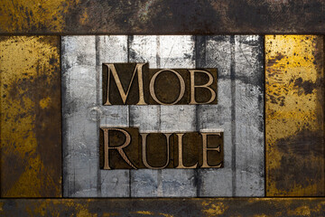 Photo of real authentic typeset letters forming Mob Rule text on vintage textured silver grunge copper and gold background
