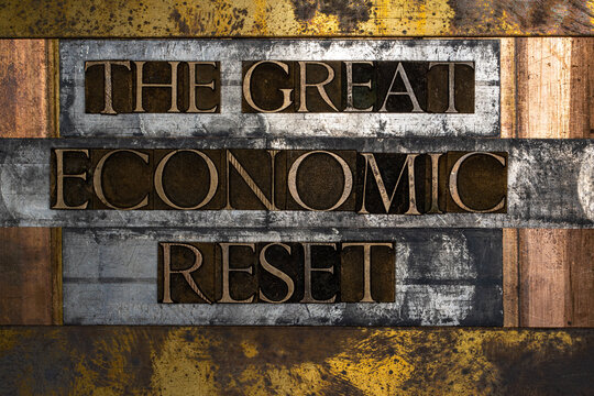 Photo of real authentic typeset letters forming The Great Economic Reset text on vintage textured silver grunge copper and gold background