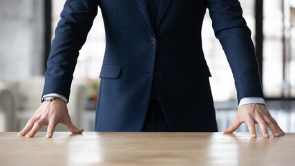 Crop close up of Caucasian businessman in formal suit stand at desk in office show confidence and power at workplace, hands of successful male leader or boss posing, leadership, success concept