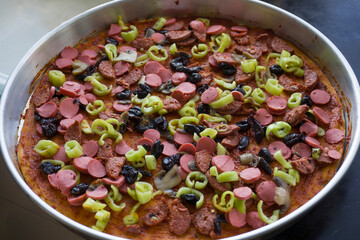 Pizza in tray with plenty of ingredients: Onion, pepperoni, cheese, pepper, sauce, lots of vegetables.