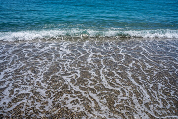 Foamy wave reaching the calm beach. Front view.
