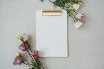 Blank paper sheet clipboard pad with mockup copy space, roses flowers on neutral grey background. Flat lay, top view minimal business template © Floral Deco