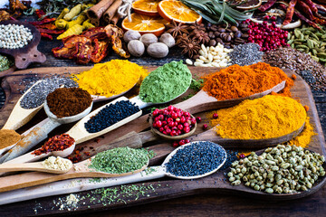 Many colorful spices, herbs and dried fruits on the wooden rustic table