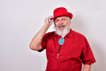 Coureous old man tipping his hat..Old man dressed in red derby hat, red shirt and large bolo tie is tipping his hat.