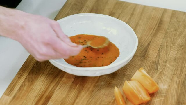 Close up of man putting a sea buckthorn sauce onto the plate with spoon. 4K