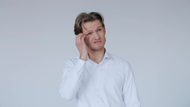 Handsome guy wearing white shirt looks confused and shrugs his shoulders. Uncomfortable, surprise facial expression.