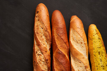 Three crispy french baguettes lie on an old wooden table with free space for text