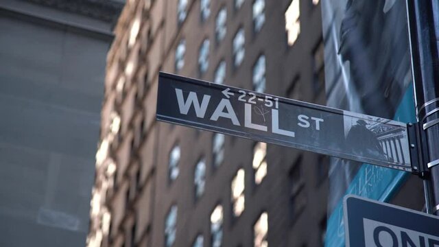 WALL STREET Spelled & Written Street Sign in the Middle of Manhattan, New York, with a Large Building Background.
