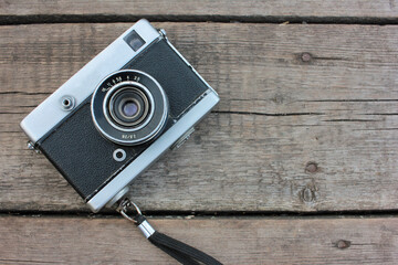Old vintage film camera on rough wooden background with copy space. Top view