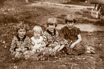 Germany - CIRCA 1920s: Group photo of four small girls sitting on grass in garden. Vintage archive Art Deco era photography