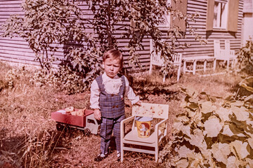 Latvia - CIRCA 1969s: Portrait of boy playing in garden. Vintage coloured photography