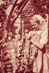Latvia - CIRCA 1930s: Portrait of girl looking for flowers in garden. Vintage archive Art Deco era photography