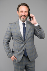 Naklejka premium mature boss talk on phone. man holding device and smiling. speak to colleague. technology bring success. successful businessman deal with problem online. agile business