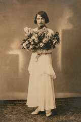 Latvia - CIRCA 1930: Wedding portrait of female standing with flowers in studio, Vintage Carte de Viste Art Deco era photo