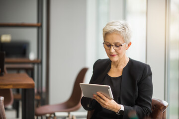 beautiful stylish woman aged with a tablet in her hands at work