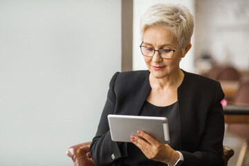 beautiful stylish woman aged with a tablet in her hands at work
