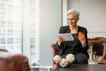 beautiful stylish woman aged with a tablet in her hands at work