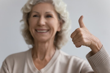 Close up of smiling mature 50s woman show thumb up recommending good service in retirement house, happy satisfied elderly female client give recommendation to medicine, elderly healthcare concept