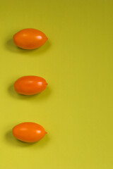 Fototapeta na wymiar Orange tomato on olive color background. Vertical position. Flat lay. Copy space.