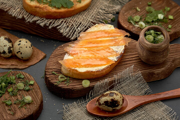 Cheese and trout sandwich on a wooden Board. Diet Breakfast sandwich with red fish, quail eggs and greens.