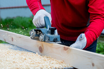  A man's hand holds an electric planing tool . The carpenter does the hardest work.