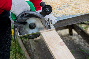 Male carpenter sawing wooden boards.