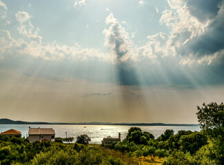 The play of light and shadow in the sky above Diklo in Zadar, Croatia and the island of Ugljan in the distance.