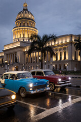 Old car on streets of Havana with Capitolio building in background with reflection on rain time. Cuba