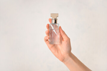Female hand with perfume on light background