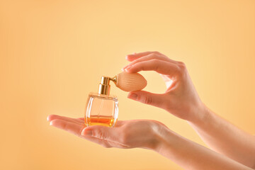 Female hands with perfume on color background