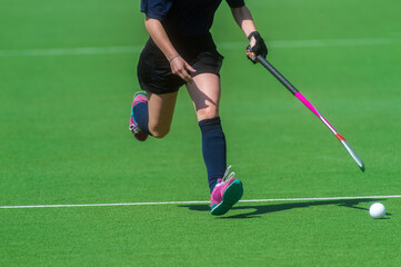Field hockey player, in possesion of the ball, running over an astroturf pitch, looking for a team...