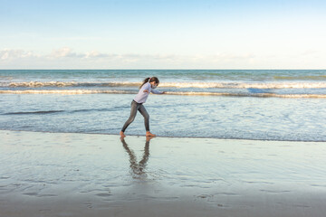 Masked young girl exercising on the beach with pirouettes © Rogerio