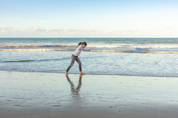 Masked young girl exercising on the beach with pirouettes