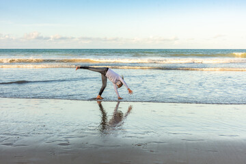 Masked young girl exercising on the beach with pirouettes