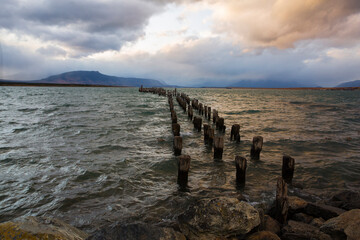 Historic dock with king cormorants perched on pilings as dusk approaches in Puerto Natales, Chile