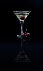Closeup glass of sweet martini dry cocktail with cherries in black background