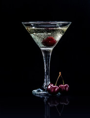 Closeup glass of sweet martini dry cocktail with cherries in black background