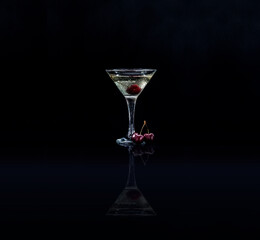 Closeup glass of sweet martini dry cocktail with cherries in black background