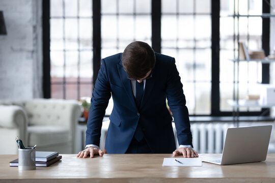 Upset unsuccessful Caucasian businessman stand at desk in office feel stressed after business startup failure, unhappy distressed male boss director stressed with company bankruptcy, money loss