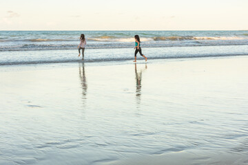 Fototapeta na wymiar Children running in the water on the beach on a beautiful day