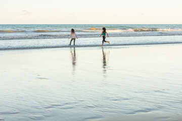 Fototapeta na wymiar Children running in the water on the beach on a beautiful day