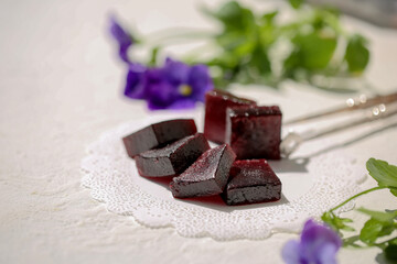 On a white table, marmalade is dark red in color from grapes.
