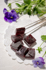 On a white table, marmalade is dark red in color from grapes.
