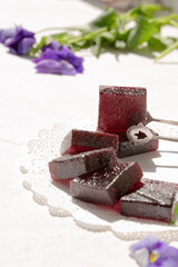 On a white table, marmalade is dark red in color from grapes.
