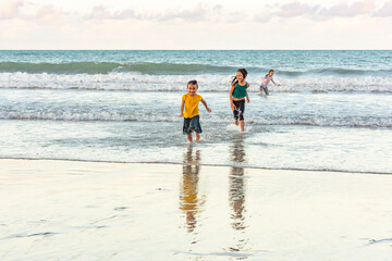 Children running in the water on the beach on a beautiful day