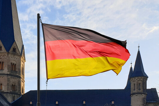 German flag. Background blue sky and spires of Bonn