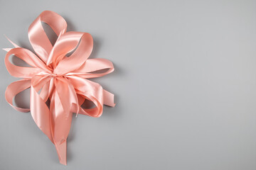 Pink silk bow on grey background. Space for text, top view