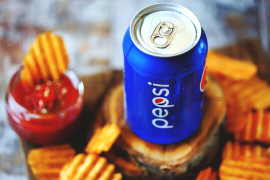 Kharkiv / Ukraine - June 07, 2020: Pepsi Can and chips with sauce. Selective focus. Macro. The composition of Pepsi and potato chips. Unhealthy food. American snack.