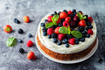 Cake with cream cheese frosting, mint leaves and strawberries, blueberries; blackberries and raspberries