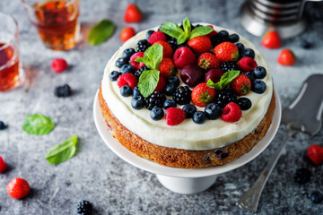 Cake with cream cheese frosting, mint leaves and strawberries, blueberries; blackberries and raspberries